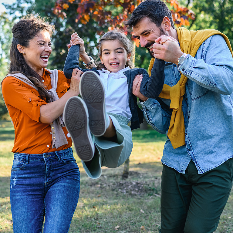 Happy parents and their daughter enjoying autumn in the park.